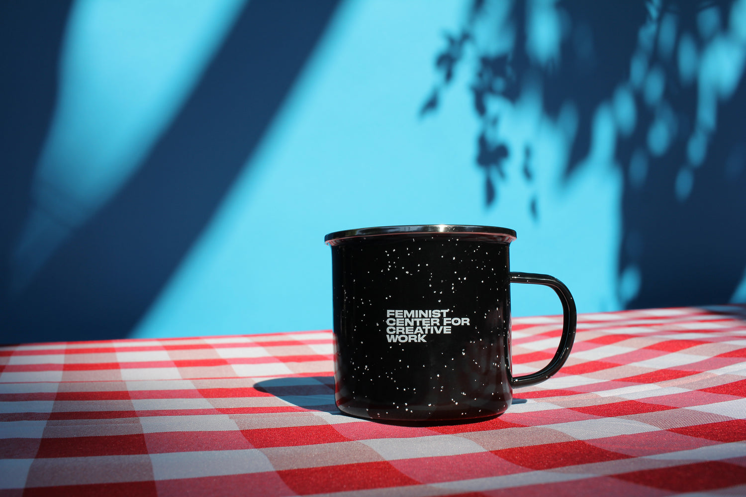 Black FCCW enameled mug with speckles on a tablecloth